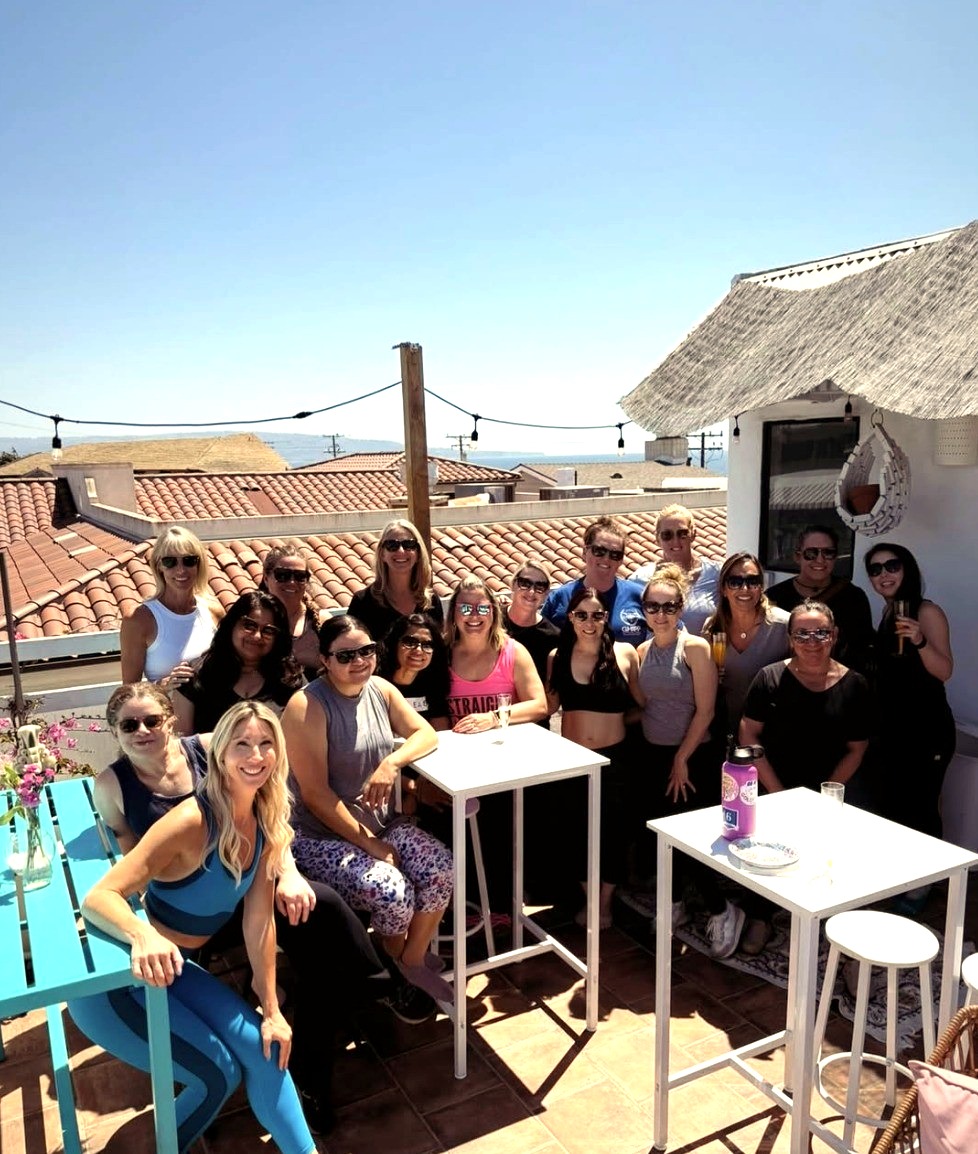 A smiling group of women gathered on the Tropical Refuge rooftop patio celebrating together